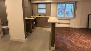 Een moderne keuken met een inbouwoven, een spoelbak en een raam met uitzicht op een stadsgezicht.