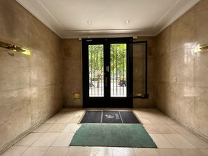 A hotel entrance with a tiled floor, a green mat, and a glass door with a metal gate. - Beautiful 1 bedroom apartment in the center of Buenos Aires city (City of Buenos Aires)