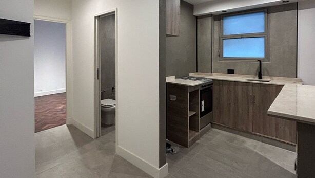 Een moderne keuken met inbouwapparatuur, een raam en een apart toilet.