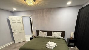 A bedroom with a large bed, a nightstand, a lamp, and a door. - Delightful 3-bedroom house in charming Tucker (Tucker)