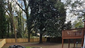A concrete patio area with a wooden deck and a tree in the background. - Delightful 3-bedroom house in charming Tucker (Tucker)
