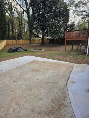 A concrete patio area with a wooden deck and a tree in the background. - Delightful 3-bedroom house in charming Tucker (Tucker)