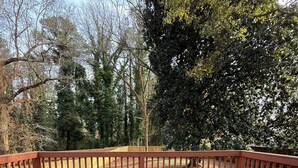 A wooden deck with a metal table and chairs, surrounded by a wooden railing. - Delightful 3-bedroom house in charming Tucker (Tucker)