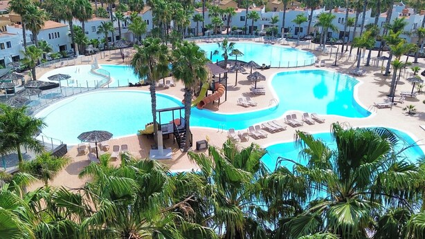 Ein Resort mit mehreren Swimmingpools, Palmen und Liegebereichen.