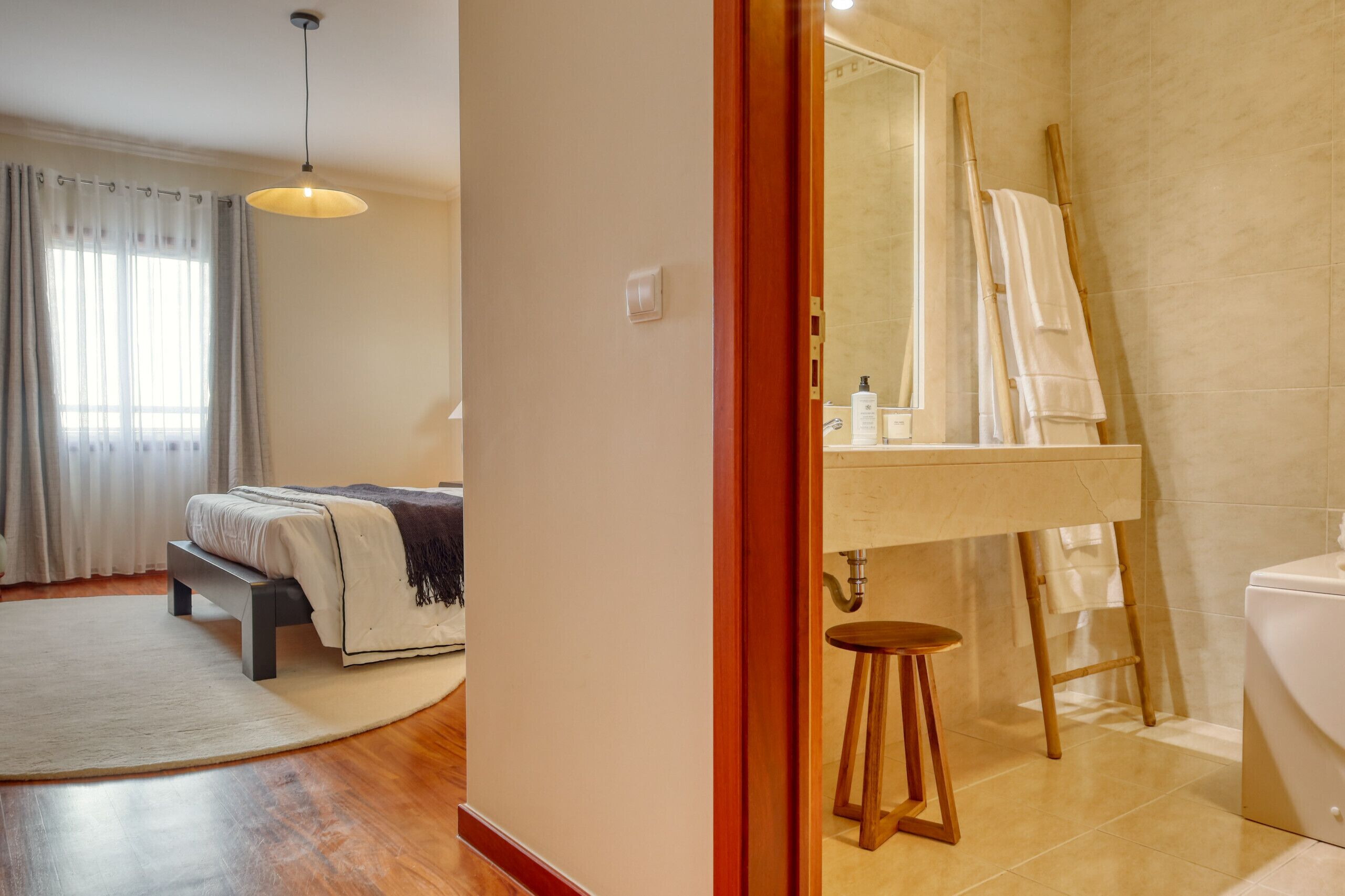 Une chambre à coucher avec un lit, une table de chevet et une grande fenêtre avec des rideaux.