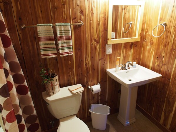 A wooden-paneled bathroom with a toilet, sink, and towel rack. - The Danville (Danville)