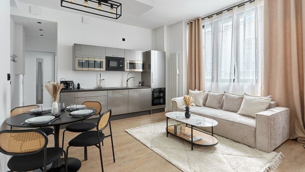 Ein modernes Wohnzimmer mit einer Couch, einem Couchtisch und einem Essbereich mit Stühlen und einem Tisch, der für eine Mahlzeit gedeckt ist.