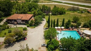 Vista aérea de una propiedad con piscina, un edificio grande y zonas verdes circundantes.