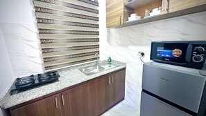 A kitchen with a gas stove, a sink, a microwave, and a refrigerator. - Welcoming 1-bedroom apartment with AC in vibrant (Ikeja)
