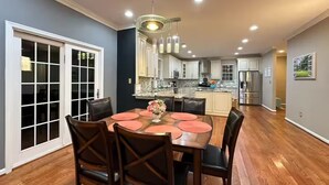 Una cocina moderna con una isla central, electrodomésticos de acero inoxidable y un comedor con mesa y sillas de madera.