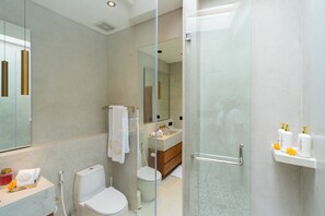 Een moderne badkamer met een glazen douchecabine, toilet, wastafel en badkamermeubel.