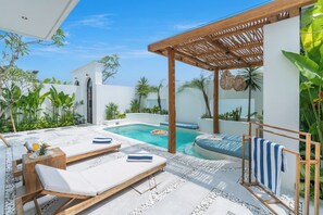 Un espace aménagé au bord de la piscine, avec des chaises longues, une petite table sur laquelle est posée une boisson et une pergola en bois.