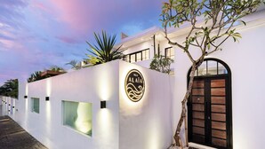 Una villa moderna con fachada blanca, una puerta negra y un letrero que dice 'Villa Alaiá'.
