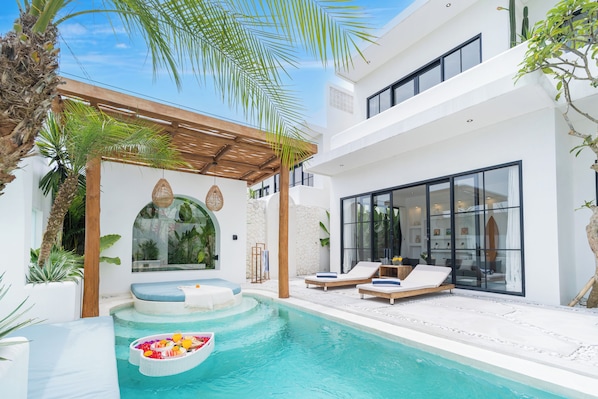 Een modern zwembadgedeelte met ligbedden, een jacuzzi en een pergola.
