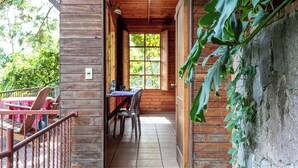 Una cabaña de madera con comedor, una mesa y sillas, y vistas de vegetación afuera.