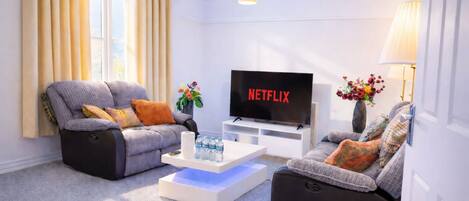 A modern living room with two sofas, a coffee table, a TV, and a lamp.
