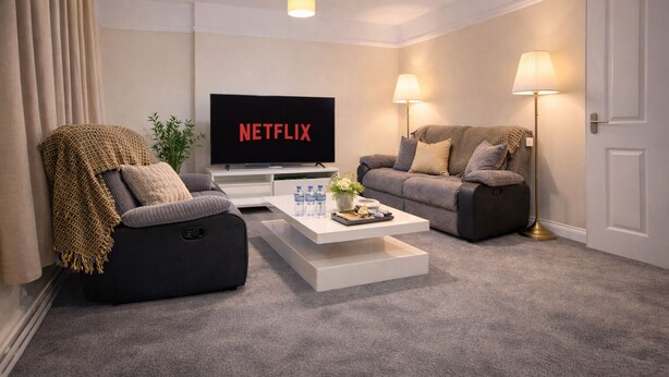Una sala de estar moderna con un televisor de pantalla plana, dos sofás, una mesa de centro y dos lámparas de pie.