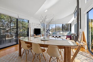 Ein modernes Wohnzimmer mit einem Glastisch, bequemen Sitzgelegenheiten und einem großen Fenster mit Blick ins Freie.