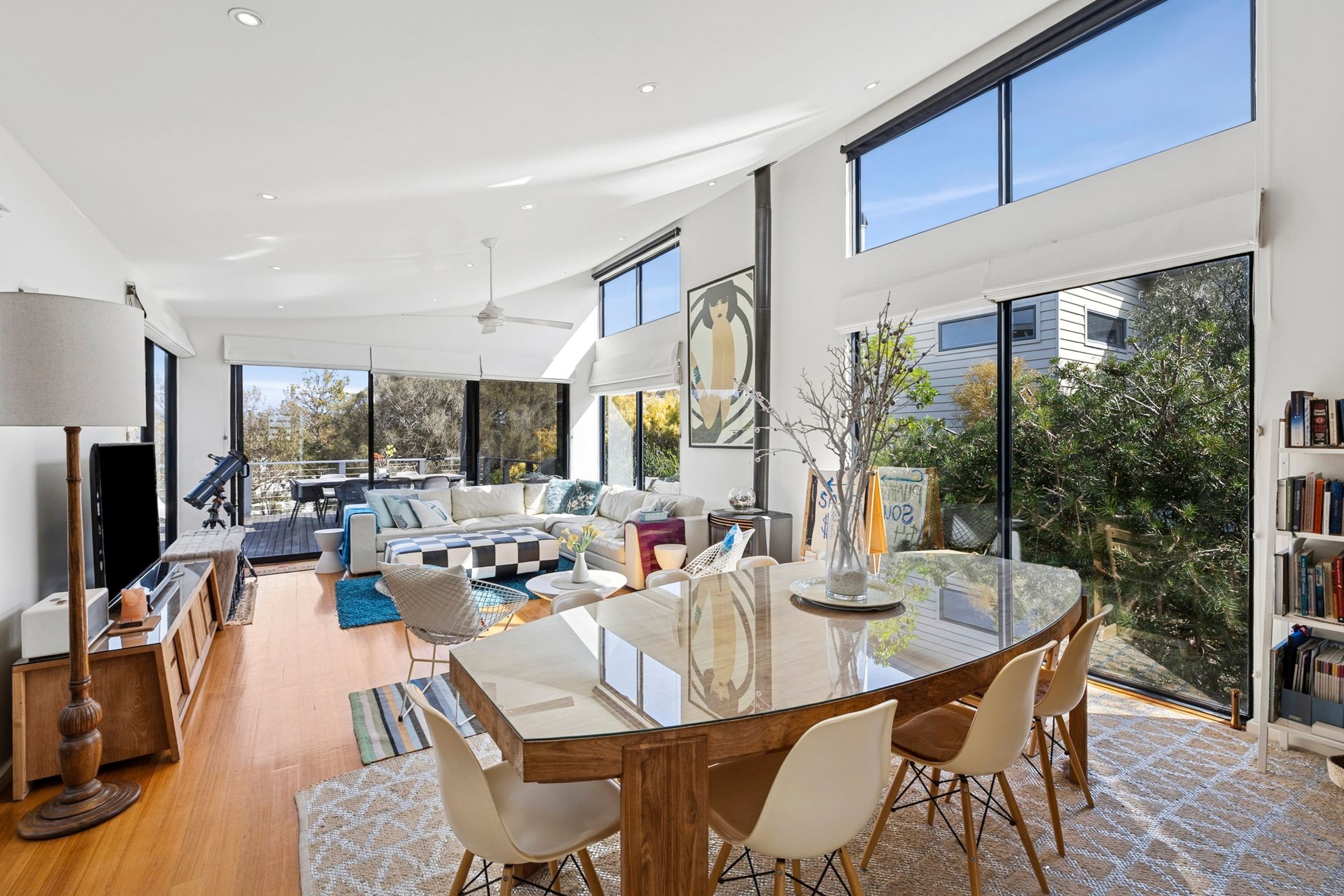 Un vaste espace de vie comprenant une grande table à manger en verre, des sièges confortables et une vue sur l’extérieur.