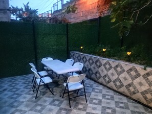 An outdoor patio with a tiled floor, a white table with chairs, and a wall with a checkered pattern. - Duplex Patio House in Old Tbilisi (Tbilisi)
