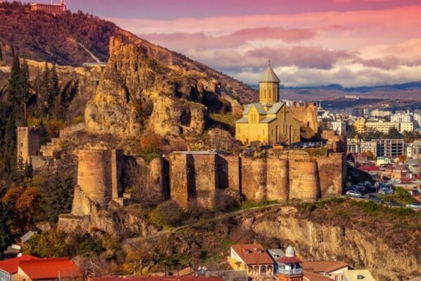 Une forteresse historique abritant une église, située sur une colline surplombant une ville.