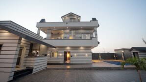 Une maison moderne à plusieurs étages, dotée d’une piscine, d’un espace extérieur couvert et d’une entrée bien éclairée.