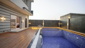 Une piscine extérieure moderne, dotée d’une terrasse en bois et d’une entrée avec une porte en verre.