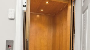Een lift met een houten interieur en een bedieningspaneel aan de wand.
