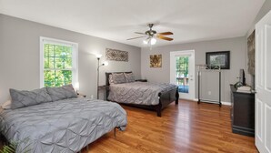 Een slaapkamer met twee bedden, een plafondventilator en een deur naar een balkon.
