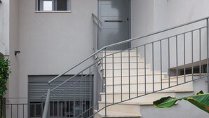 A modern building with a grey exterior, a staircase with metal railings, and a door with a window above it. - 2 Independent Apts with Yard near the City's Heart (Kalamata)