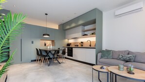 A modern kitchen with grey cabinets, a dining area with a table and chairs, and a living area with a sofa and coffee table. - 2 Independent Apts with Yard near the City's Heart (Kalamata)
