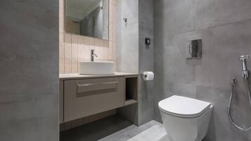 A modern bathroom with a toilet, sink, and shower.