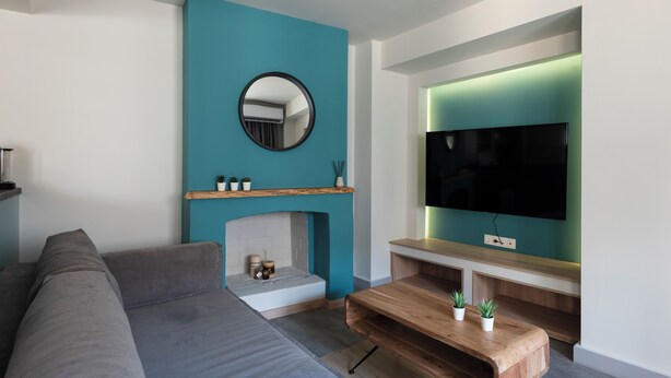 A modern living room with a grey sofa, a wooden coffee table, a fireplace, and a flat-screen TV mounted on the wall. - 2 Independent Apts with Yard near the City's Heart (Kalamata)