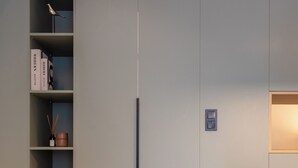 A modern kitchen with a built-in cabinet, a dining table with chairs, and a small shelf with books and a candle. - 2 Independent Apts with Yard near the City's Heart (Kalamata)