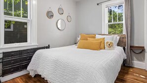 Een slaapkamer met een bed, een dressoir en een raam.