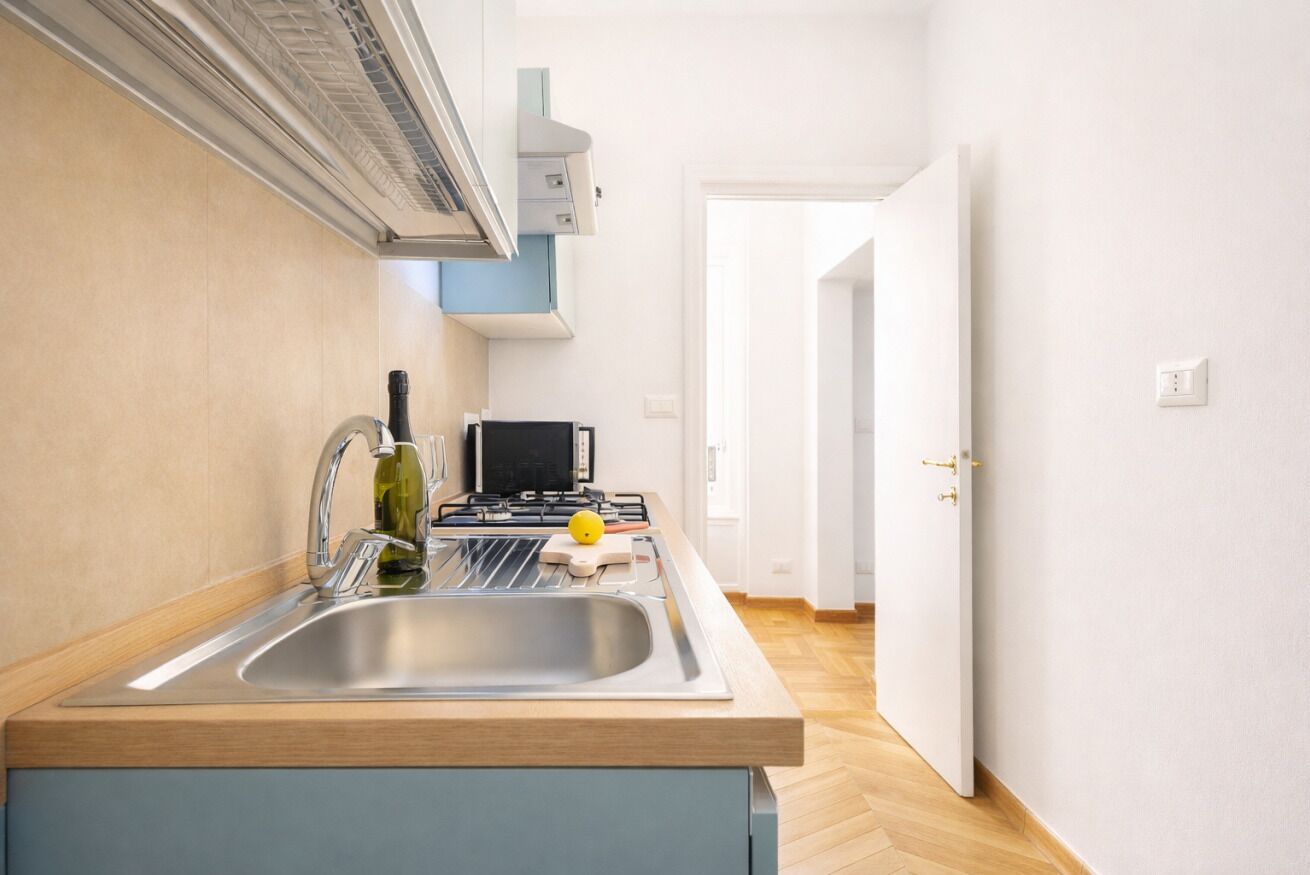 Una cucina moderna con lavello in acciaio inossidabile, piano cottura a gas e forno integrato.