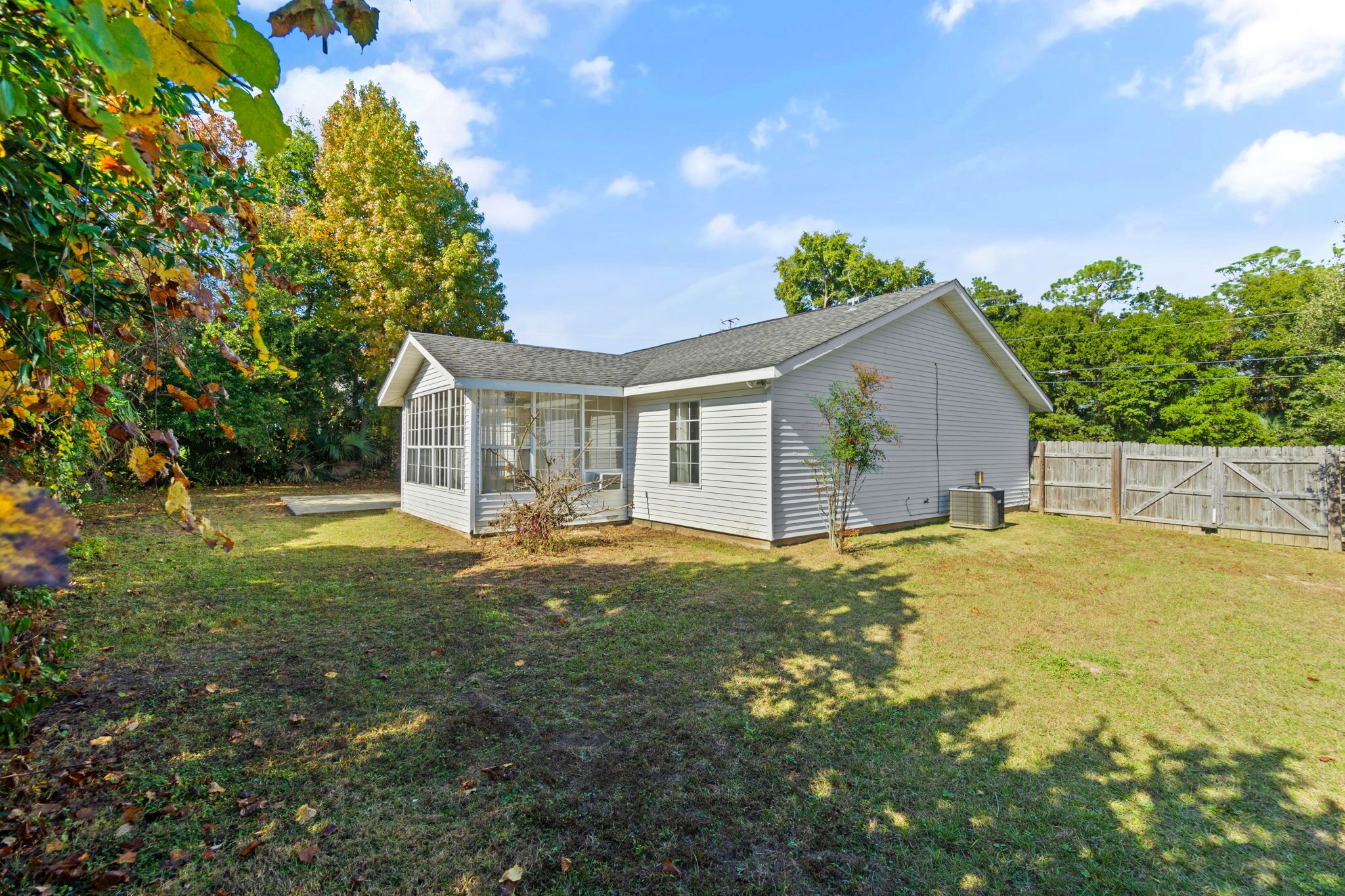 A single-story house with a covered porch, a fenced yard, and a clear sky.