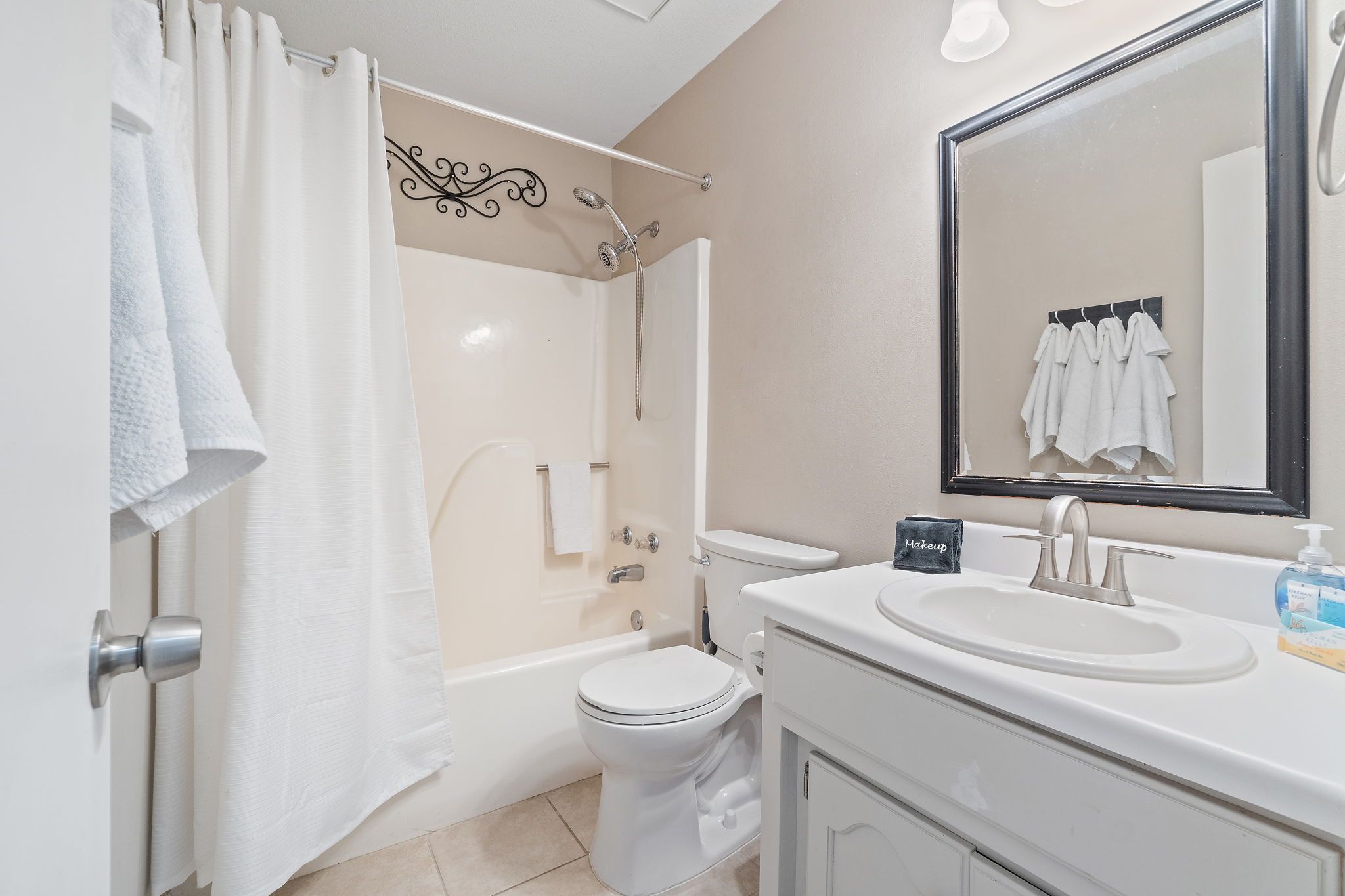 A bathroom with a bathtub, toilet, sink, and a mirror.