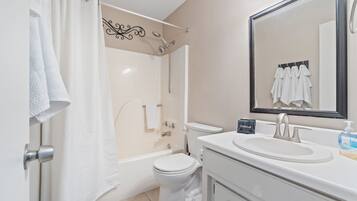 A bathroom with a bathtub, toilet, sink, and a mirror.