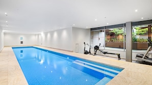 A swimming pool with exercise equipment and a view of greenery outside. - Peaceful 2-bed Apartment With Gym & Pool (Melbourne)