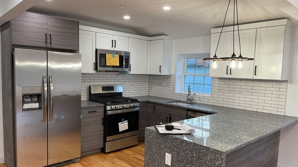 A modern kitchen with stainless steel appliances, a granite countertop, and white cabinetry.