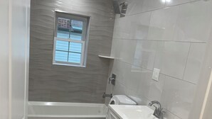 A modern bathroom with a bathtub, toilet, and vanity.