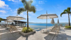 Eine Dachterrasse mit Liegestühlen, Sonnenschirmen und Blick auf das Meer.