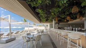Zona de bar al aire libre con asientos y vista al océano.