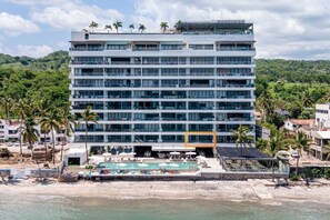 Um hotel com vários andares, piscina no terraço e localização à beira-mar.