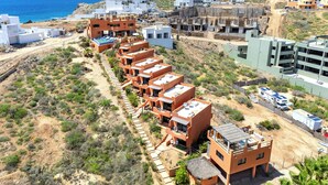 Un hôtel situé sur la côte, composé de plusieurs bâtiments, doté d’une piscine et d’un chemin de terre menant à l’entrée.