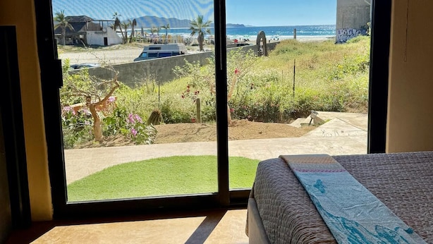 Une chambre dotée d’une grande porte-fenêtre coulissante donnant sur un balcon avec vue sur la plage et l’océan.