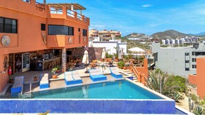 A rooftop pool area with lounge chairs, a bar, and a view of the surrounding buildings and hills. - Condo Loft next to Cerritos Beach, Pescadero BCS (Cerritos pescadero)