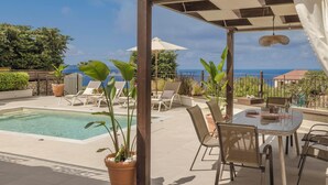 A poolside area with lounge chairs, a table, and potted plants. - Anesis - Three Bedroom Villa, Sleeps 6 (Fiskardo)