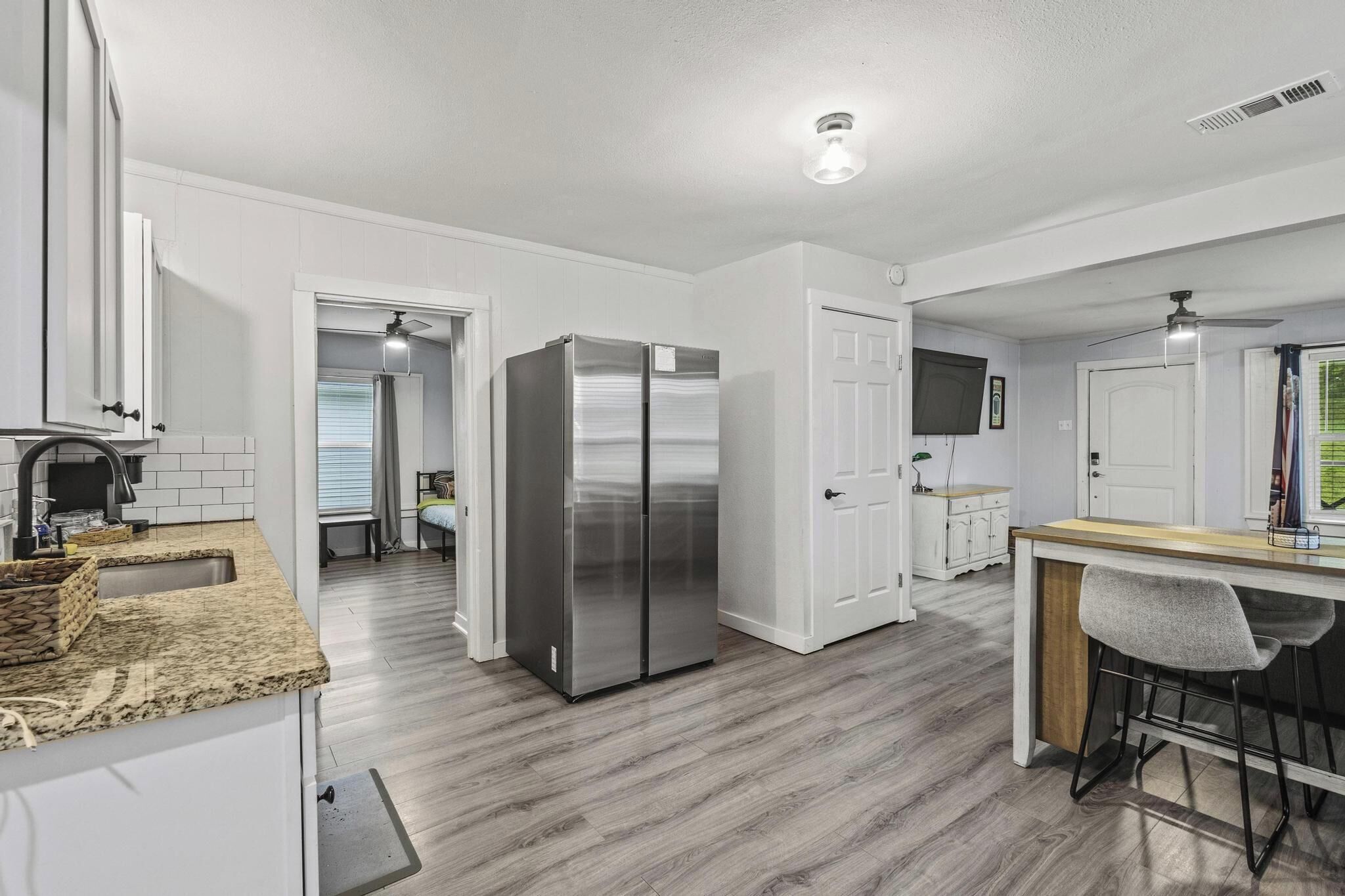 A modern kitchen with a stainless steel refrigerator, white cabinetry, and a wooden countertop.